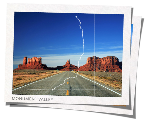 Road heading toward towering stone buttes in Monument Valley, Utah   