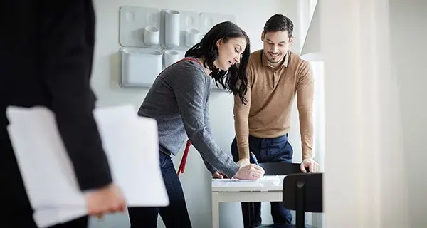 couple sign documents on desk